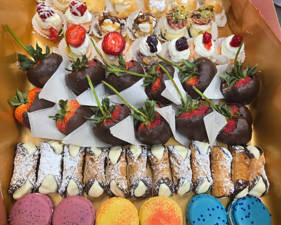 A Josef's bakery box filled with macarons, cannoli, chocolate strawberries and mini desserts